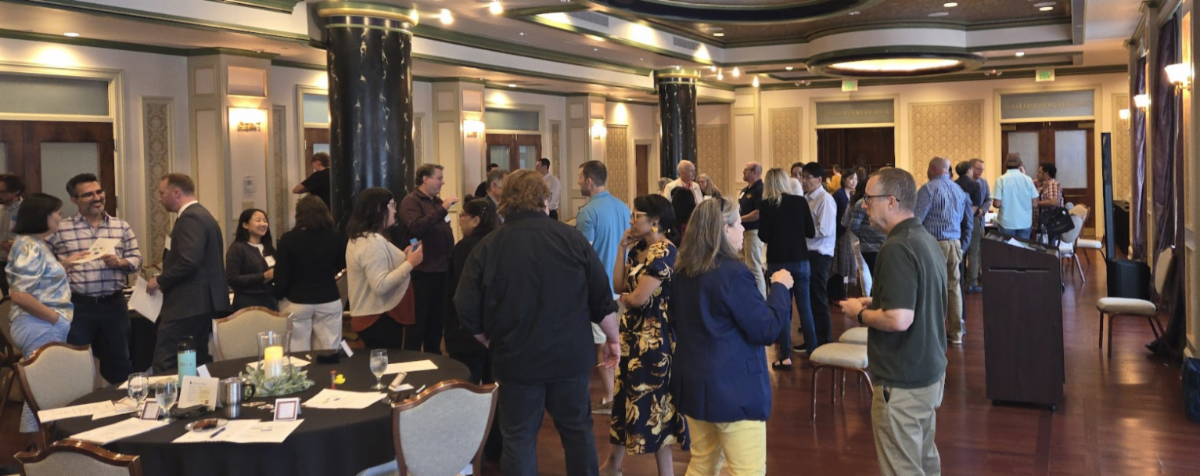 Photo of attendees standing and talking at the Generating AI Solutions event