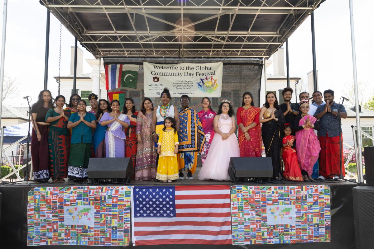Group photo of Global Community Day Festival participants on stage in 2025