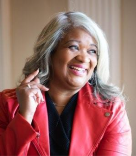 Jackeline Mejias Fuertes, Regional Director for the New Jersey Small Business Development Center at Brookdale Community College, smiling in professional red blazer and black top against a neutral background