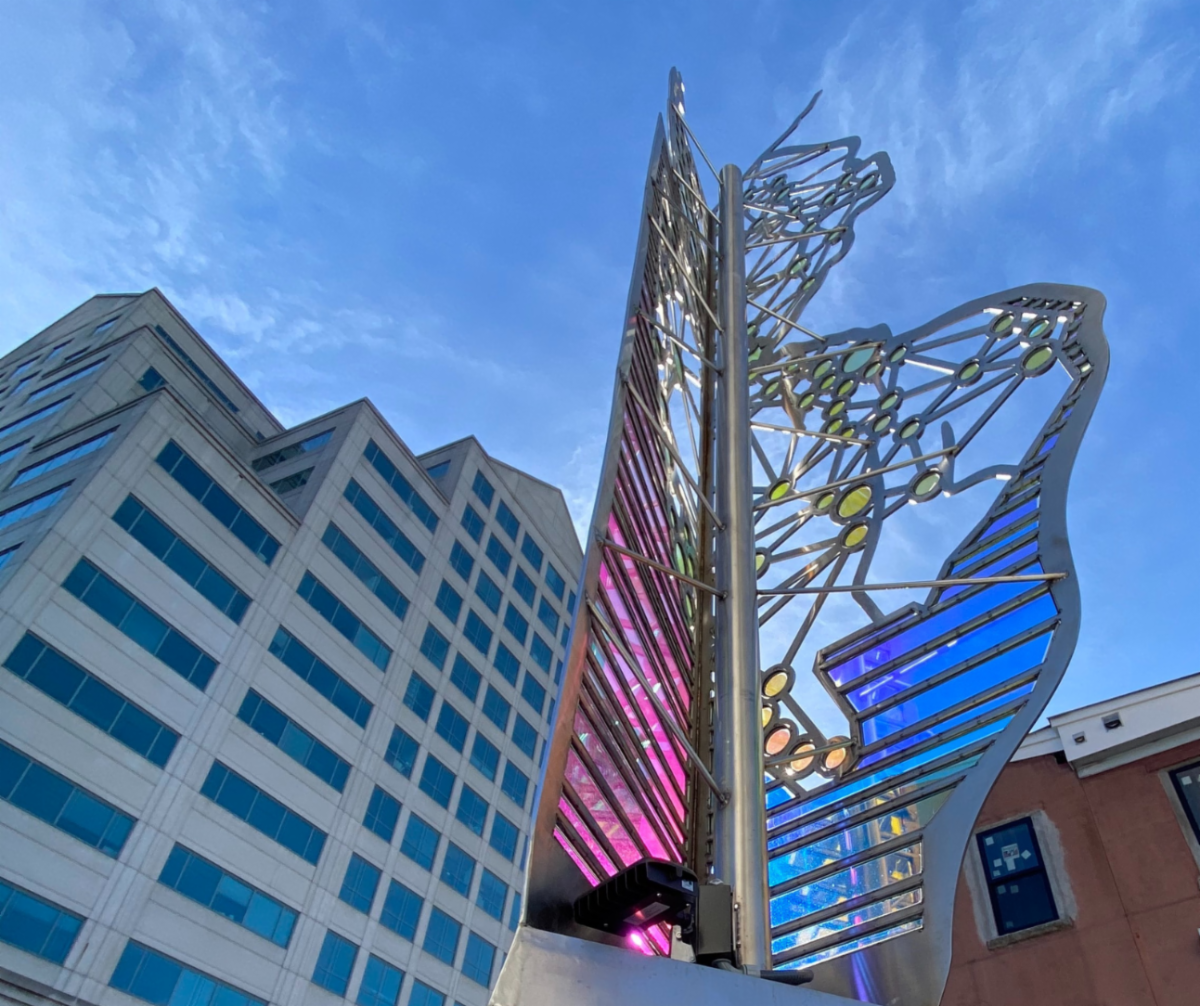 An abstract sculpture made of glass, steel, and concrete standing outside the New Jersey Department of Health on a sunny day in Trenton, NJ.