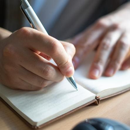 person writing on notebook