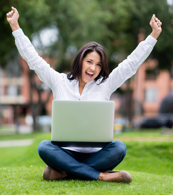 excited woman on laptop in park