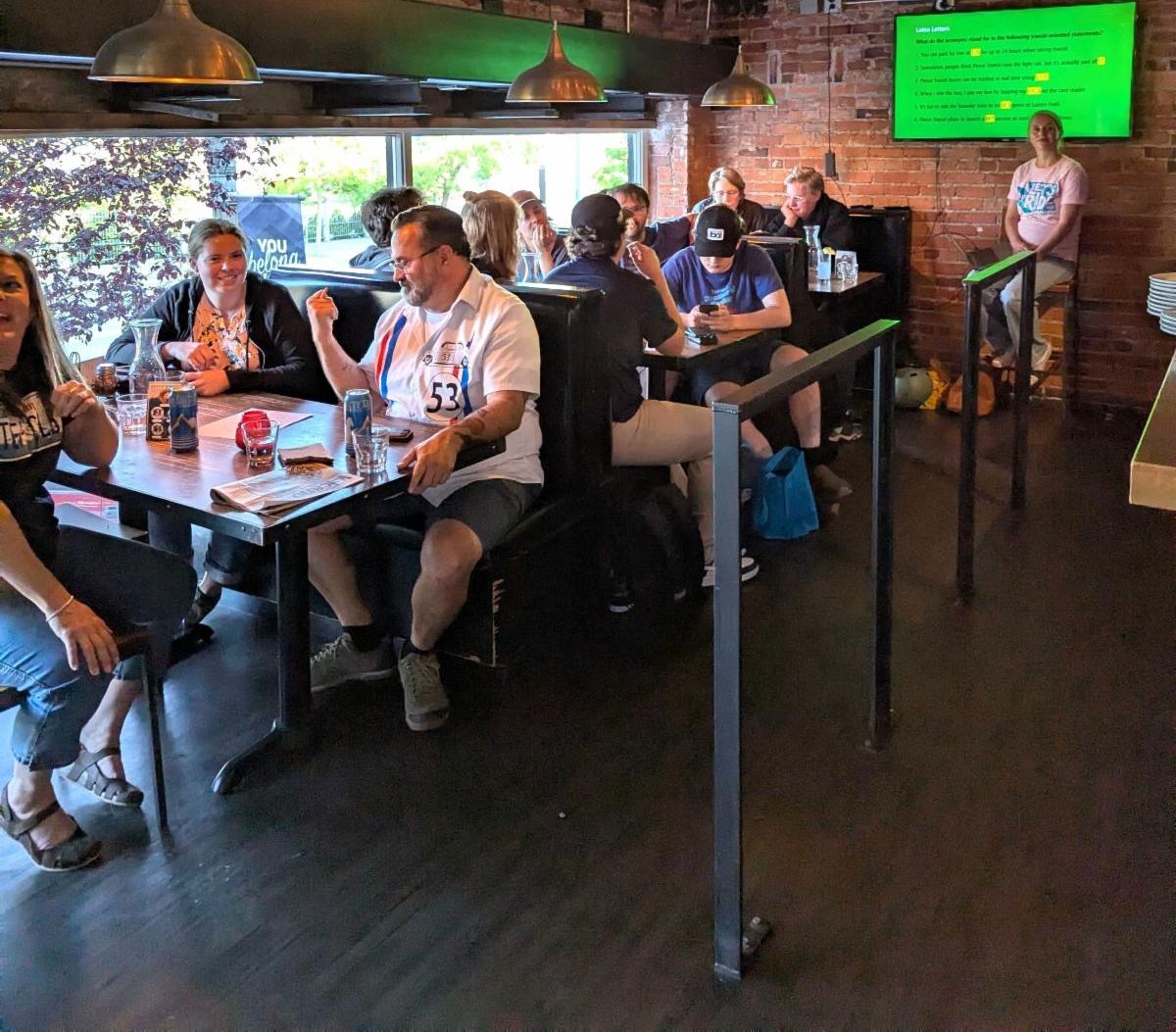 People in restaurant siting down playing trivia with screen in background
