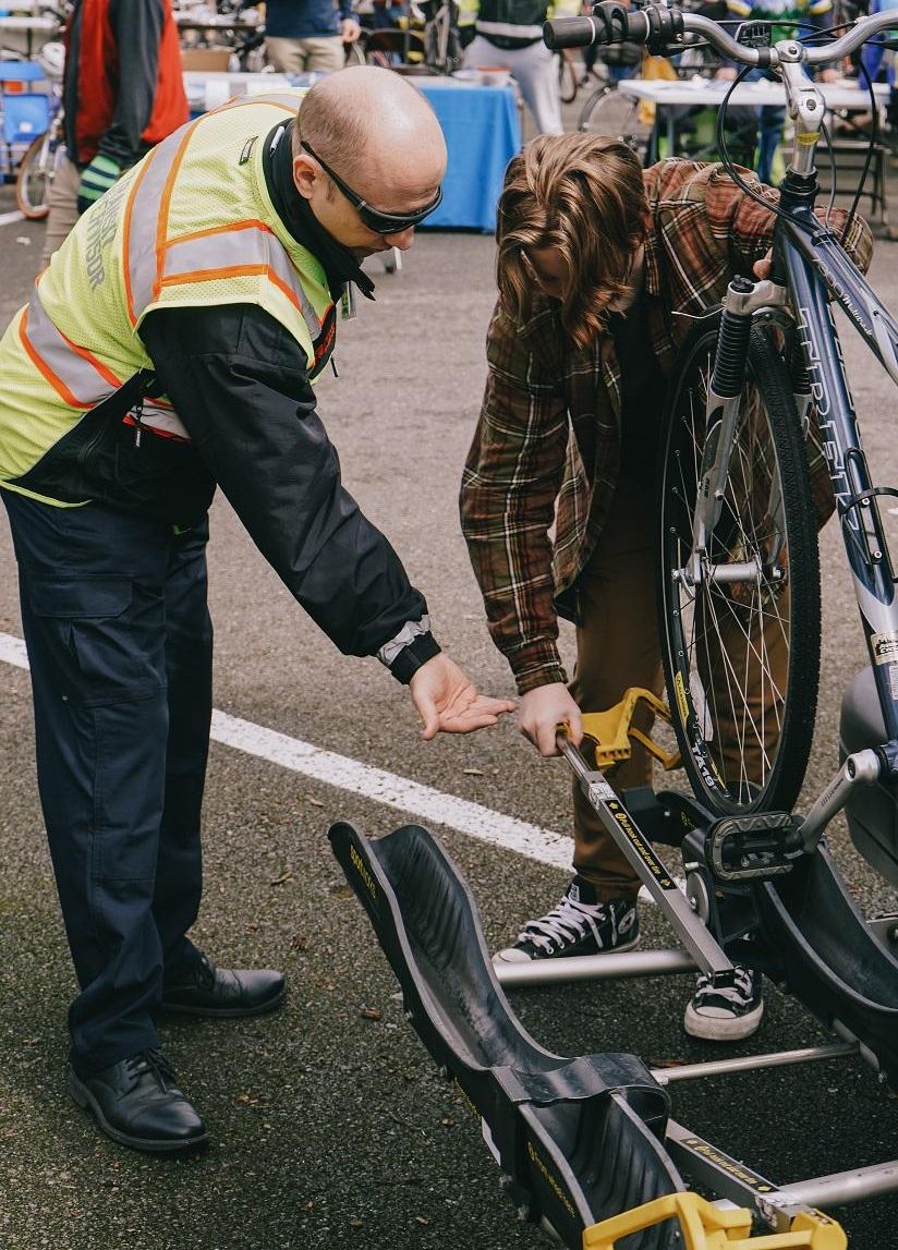Man in safety vest helping a person load a bike on the front of a bus.