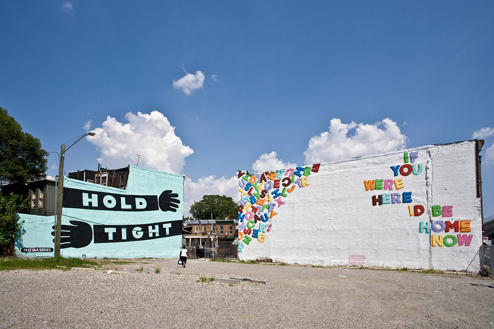two murals next to each other. one reads hold tight. one reads if you were here i'd be home now