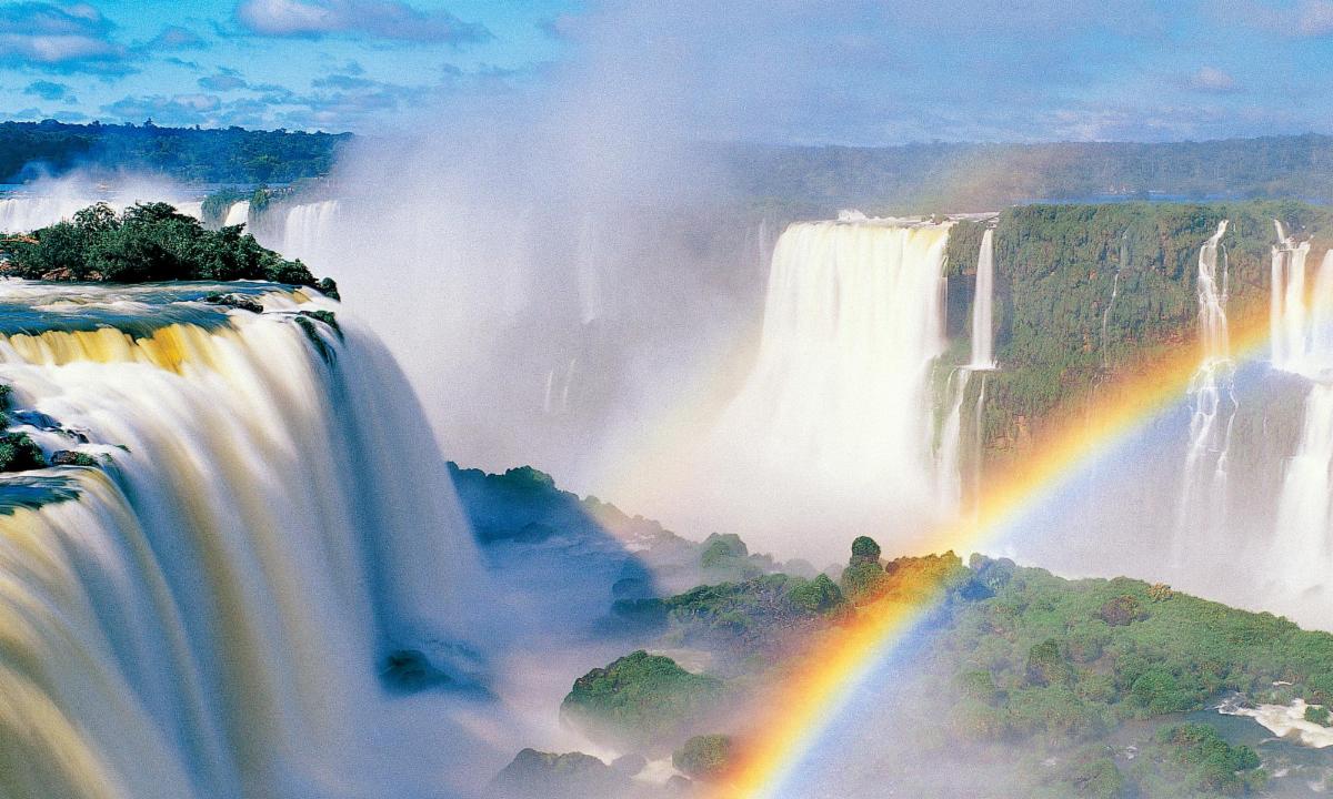 a rainbow is seen over a huge waterfall in iguazu falls