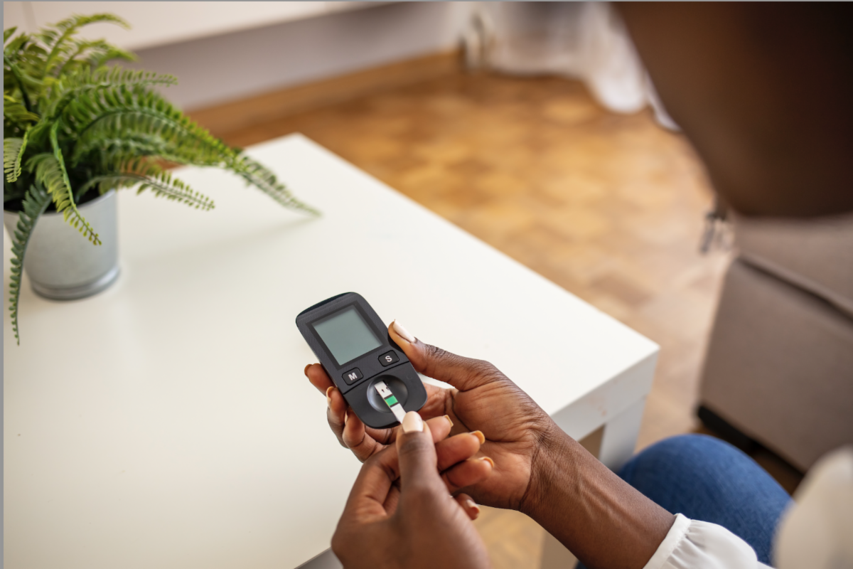 An adult putting a diabetes test strip into a blood glucose meter.  