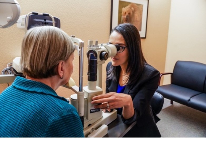 Eye doctor looking at patient's eye through a microscope.