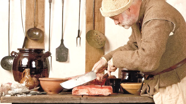 a man wields a knife to cut a piece of meat in the kitchen