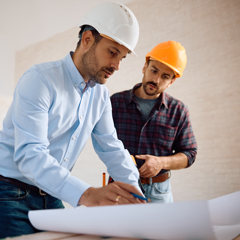 two men in hard hats looking at construction plans