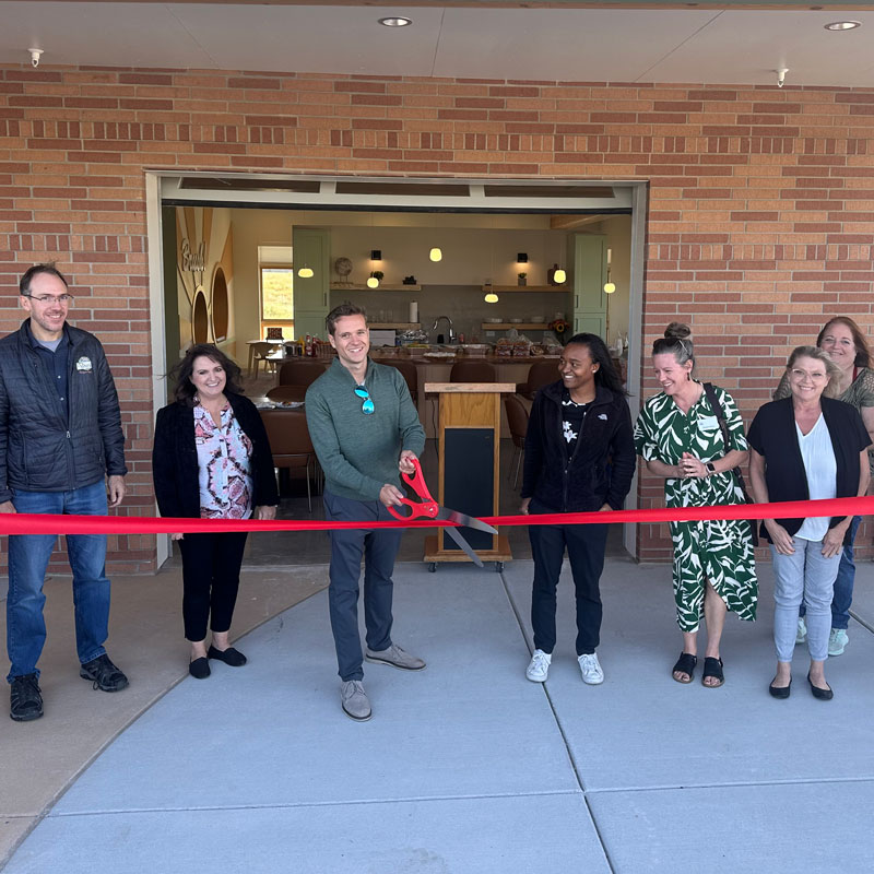 A group of people cutting a red ribbon at Meadow Vista Apartments