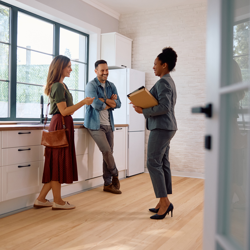 Three people standing in an empty room of a house