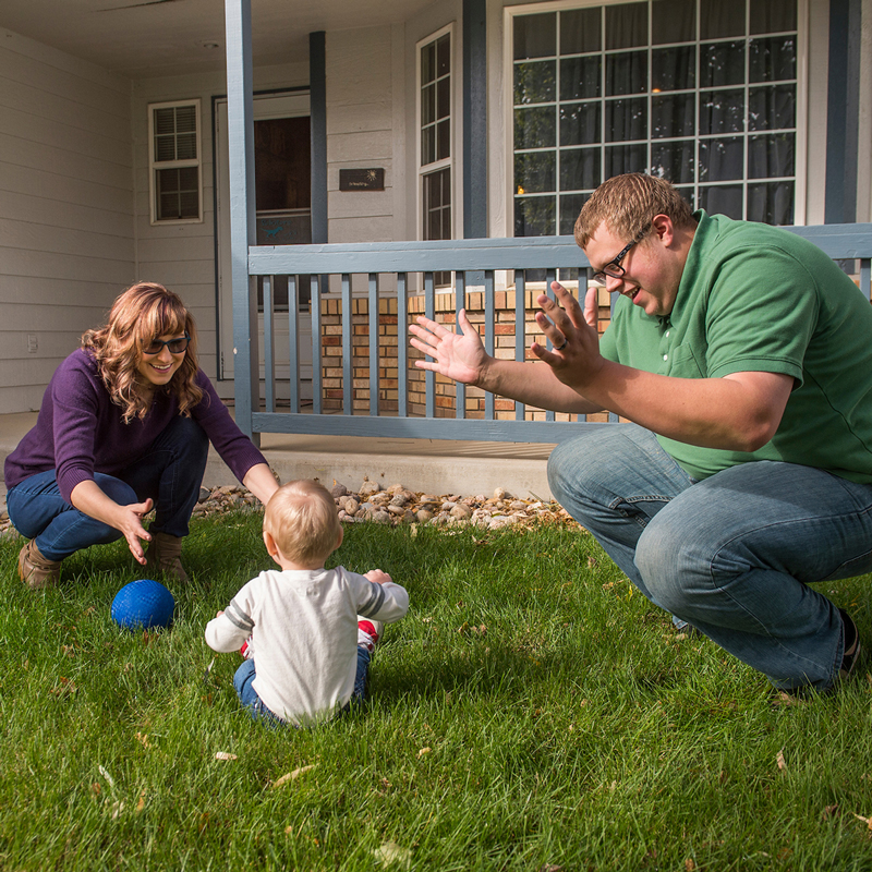 CHFA homeowners Aly and Josh playing out in the front of their home with their child.