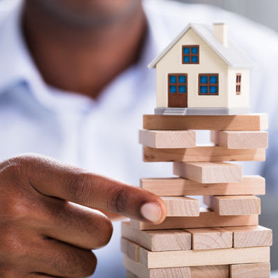a hand holding up a stack of blocks with a mini house on top