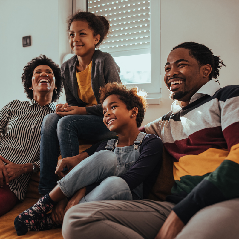 A family smiling in a living room with text that reads "building a legacy: a black homeownership series" and "colorado housing and finance authority"