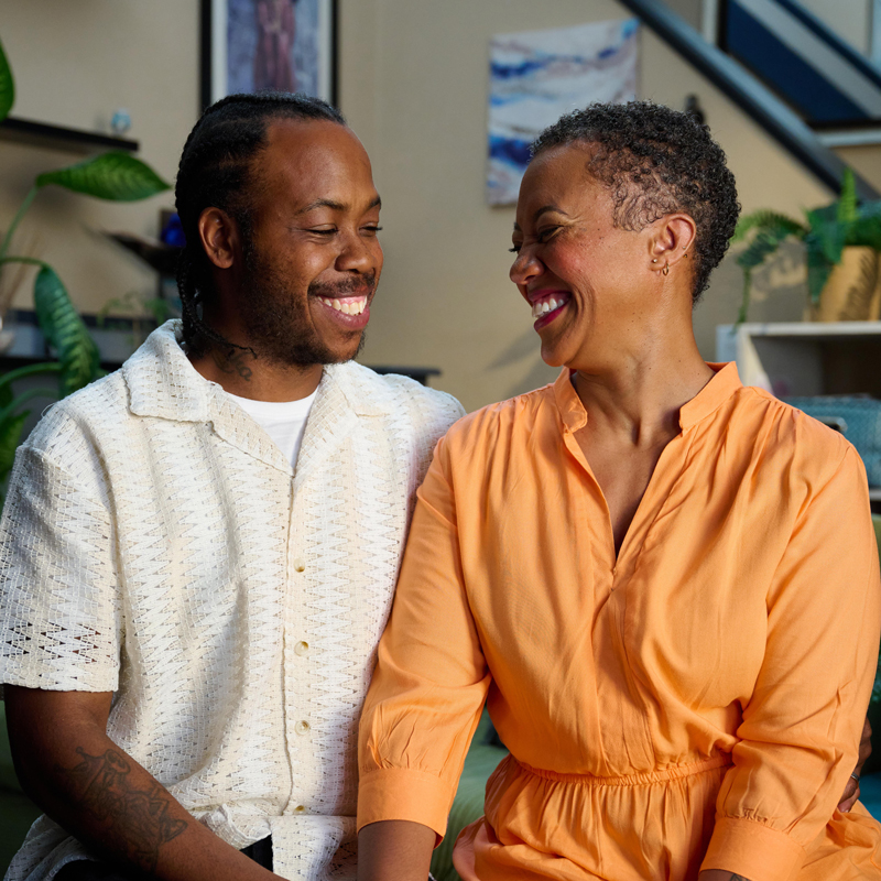 Two people looking at each other laughing and smiling.
