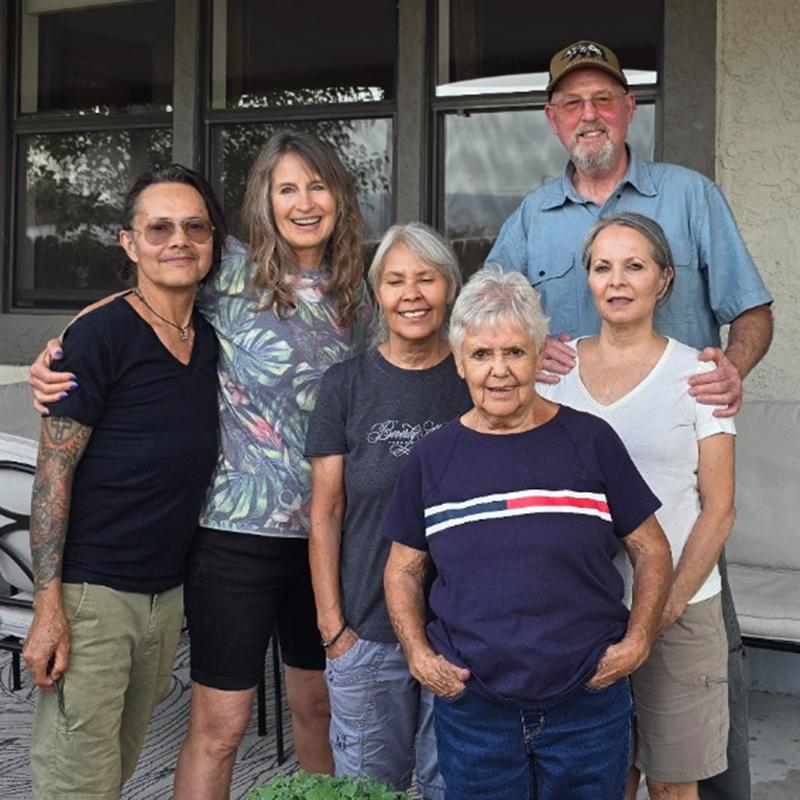 A family standing in front of a house smiling for the camera.
