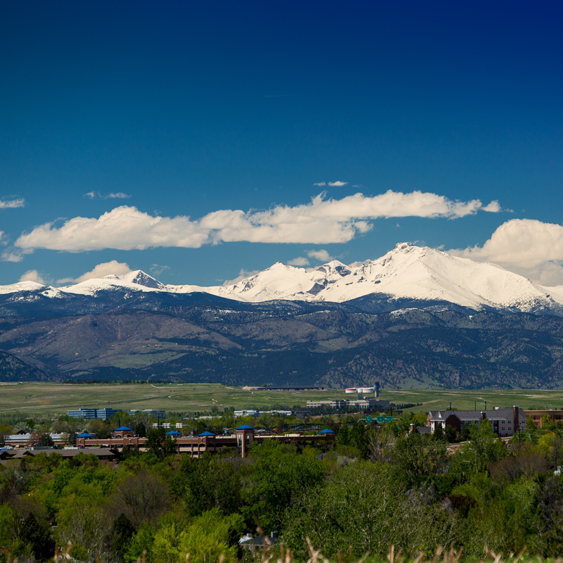 a scenic view of a town in front of mountains