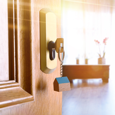 A gold key in a wood door with golden light shining on it.