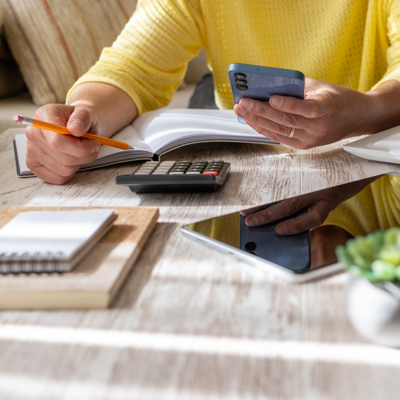 a person in a yellow shirt with a calculator phone pencil and tablet