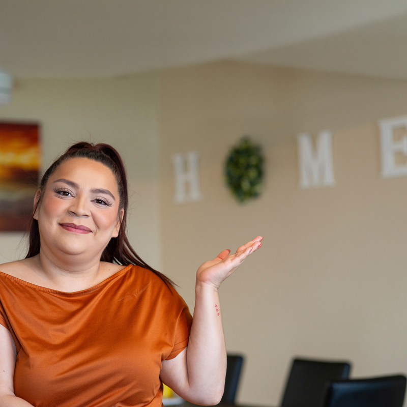 A woman pointing to a HOME sign on her wall