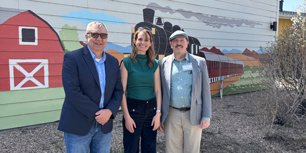 Three people standing in front of a mural on a building