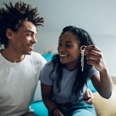 A couple sitting together where one is holding a key