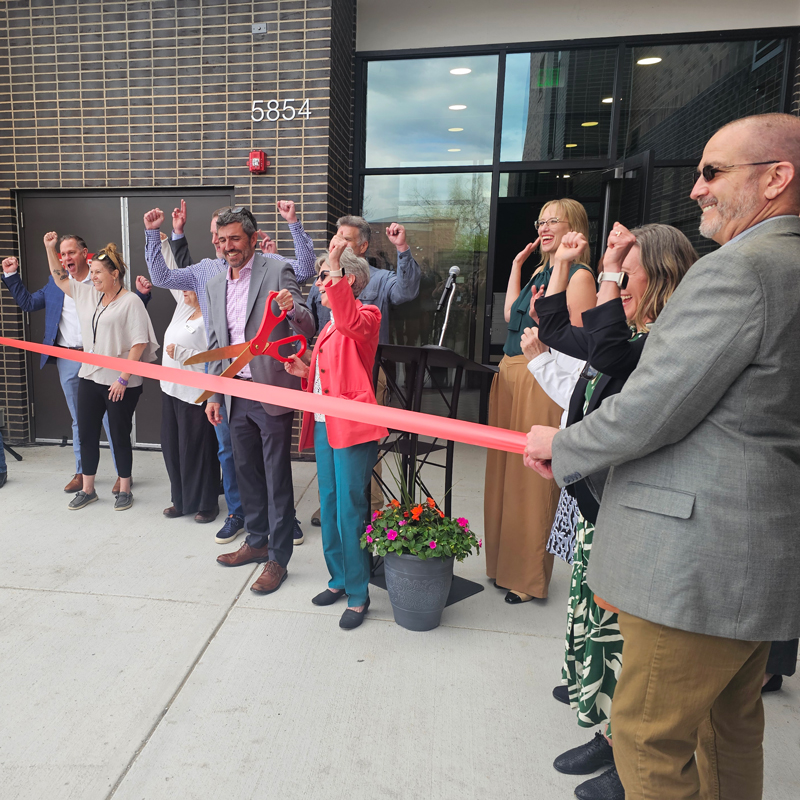 People cutting a ribbon in front of a building