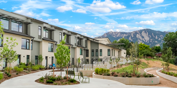 An exterior view of a multifamily building with a landscaped courtyard and blue sky.