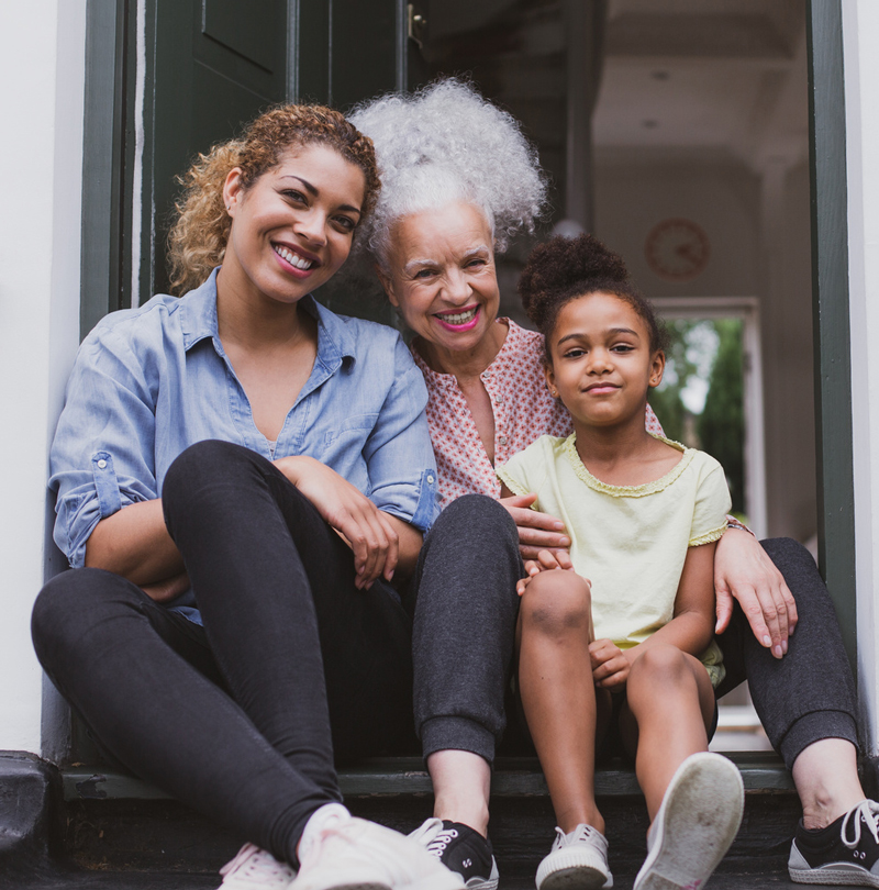 Three generations of women sitting on a front step.