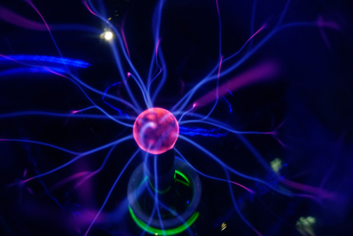 Plasma ball lamp energy_ touching glowing glass sphere concept for power_ electricity_ science and physics. Selective focus 