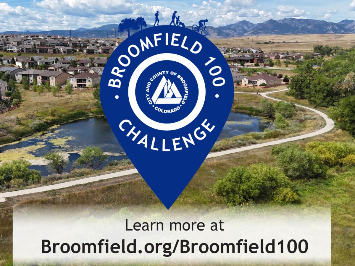 An aerial view of a Broomfield, Colorado residential neighborhood and natural area, featuring a winding paved trail, a small pond, and mountain peaks in the distance. Overlaid on the image is a large blue map pin icon containing the City and County of Broomfield logo and the text "BROOMFIELD 100 CHALLENGE". The top of the pin shows silhouettes of people engaged in outdoor activities like hiking and cycling. At the bottom of the image, a white banner includes the text "Learn more at Broomfield.org/Broomfield100"