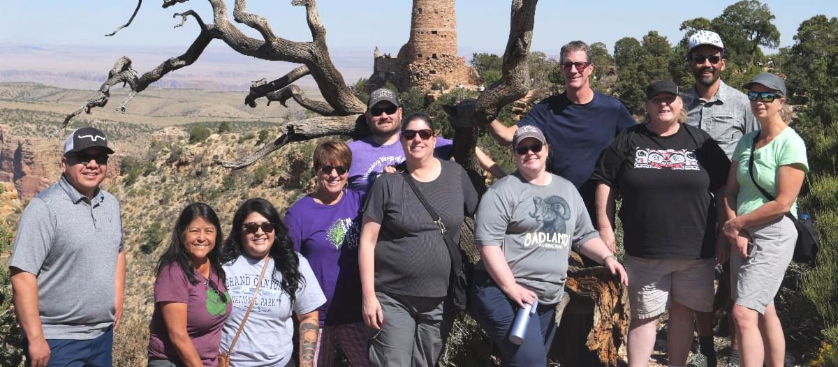 AIVRTTAC team of 11 people standing outside next to the Grand Canyon on a sunny day