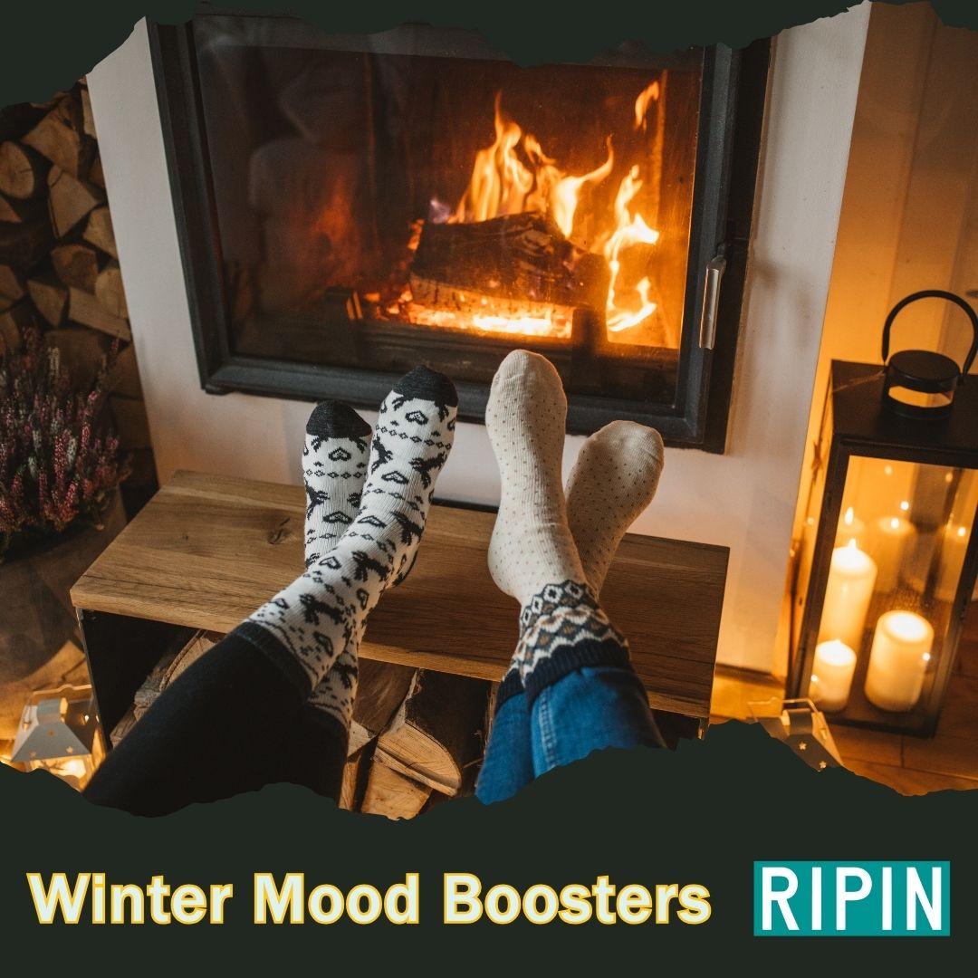 two sets of legs with socks on their feet sitting in front of a fire in a fireplace
