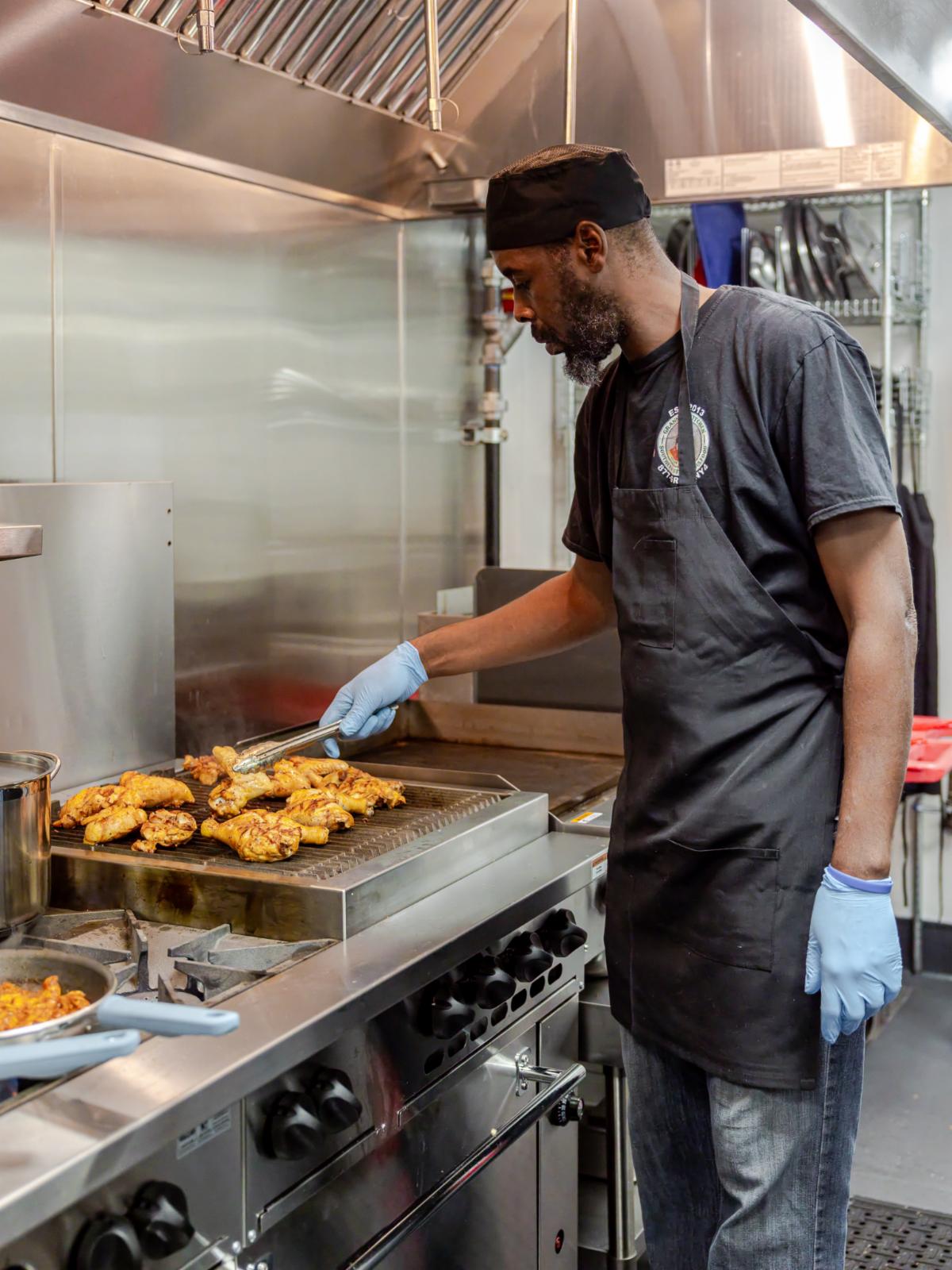 a man in a food kitchen preparing food at a grill