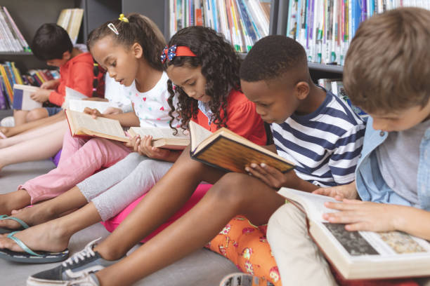 Children sitting on the floor of a classroom or library reading books