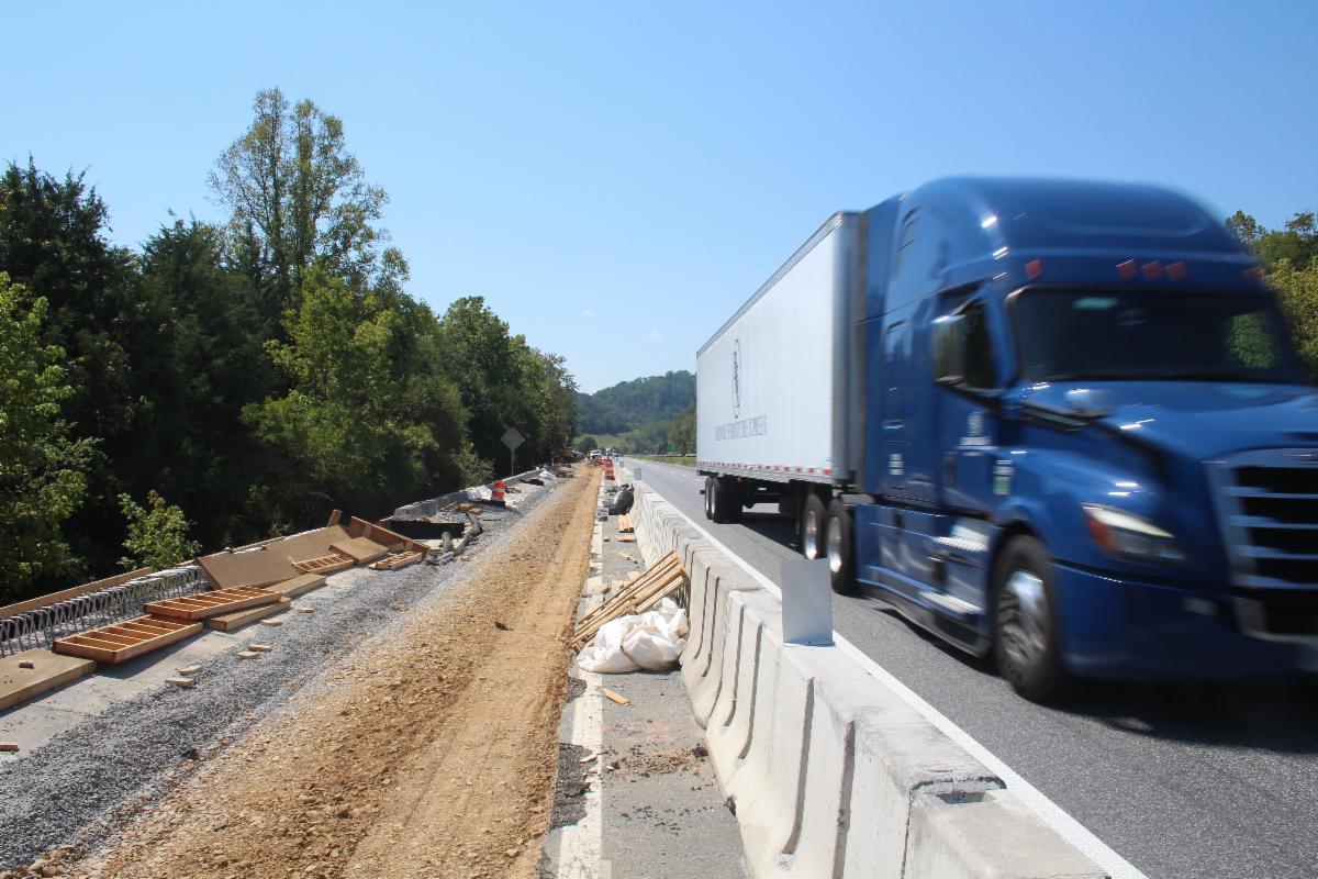 Construction to the left of roadway barrier as semi-truck passes to the right