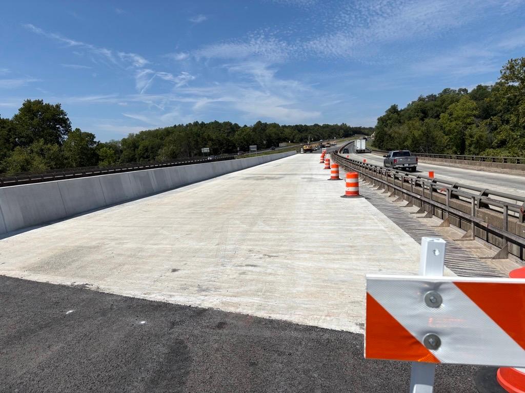 Construction barrels on top of a recently completed bridge section