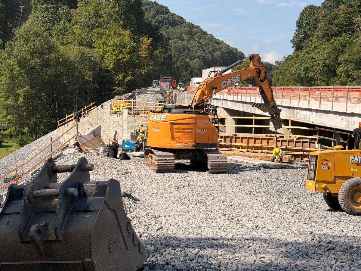 Heavy construction equipment and crews work to left of interstate