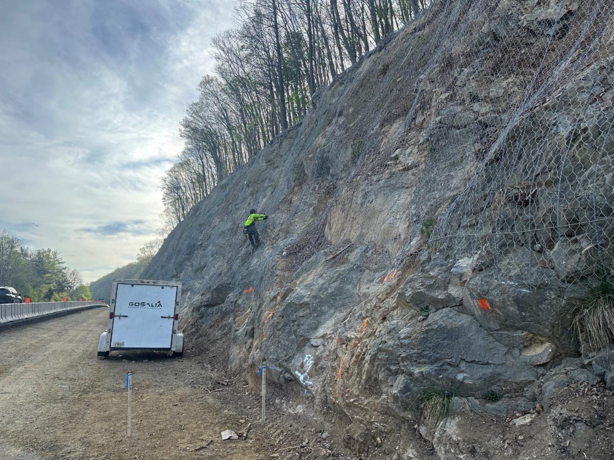 Person in PPE rappels down rock slope