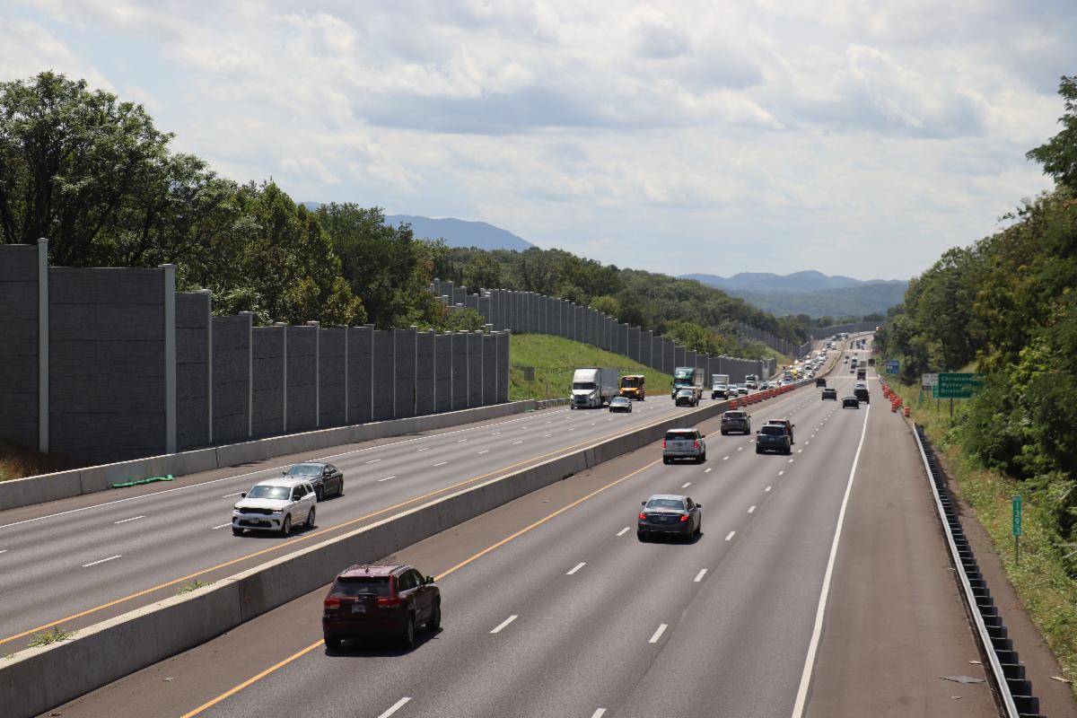 Interstate with three lanes in each direction with construction barrels in distance