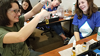 Females smiling and demonstrating water quality testing using a test tube.