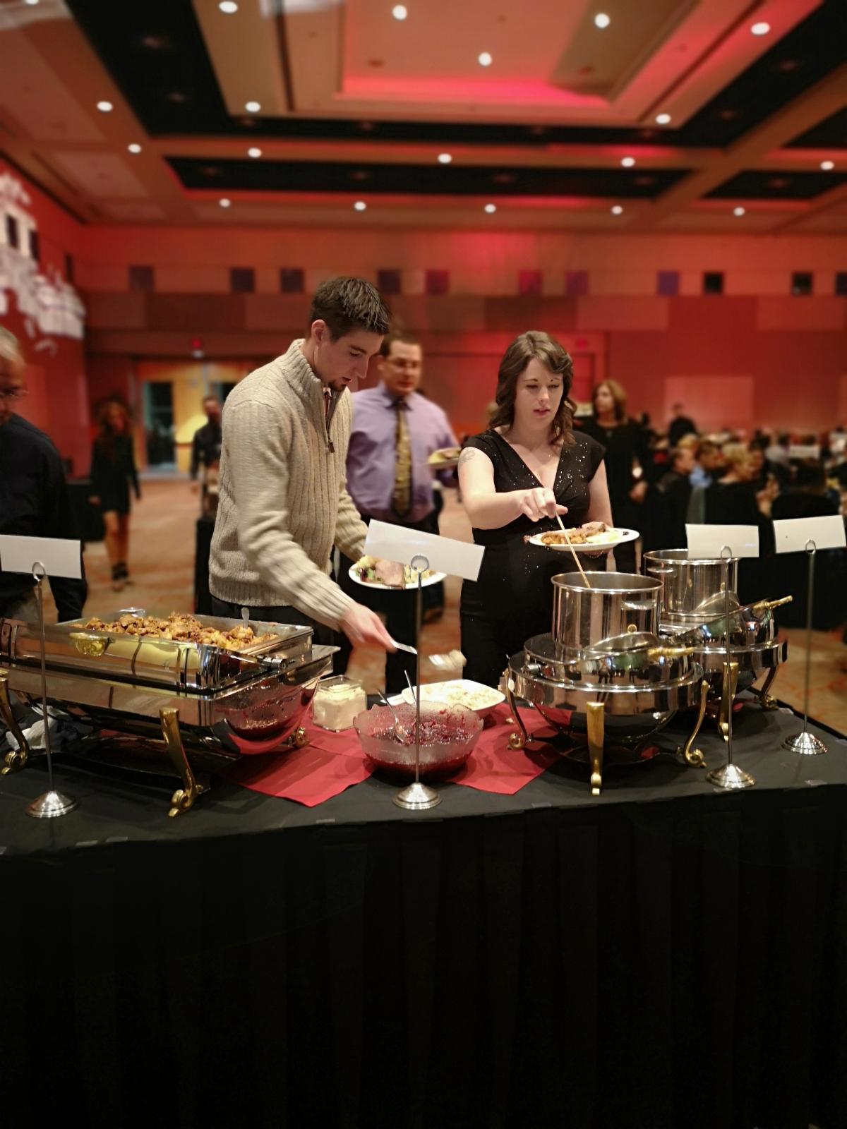 Guests pick items from the festive buffet at Christmas at our Place holiday gala.