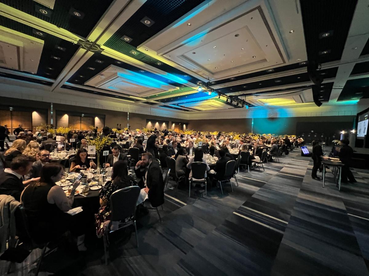Guests gather for a large dinner event in the Grand Ballroom at RBC Place London, with banquet tables, stage lighting and a presentation area visible.