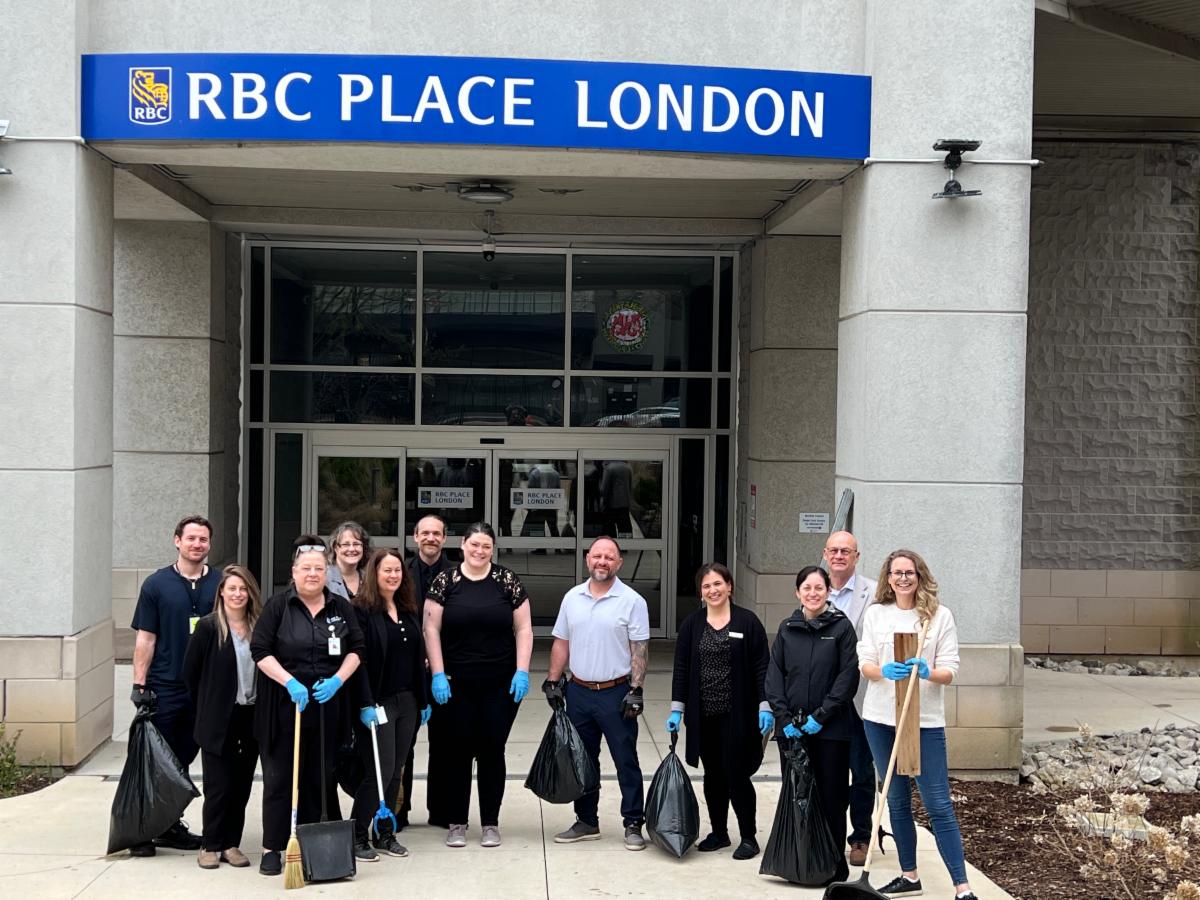 Team of RBC Place London staff participating in community cleanup event with collected garbage bags and debris.