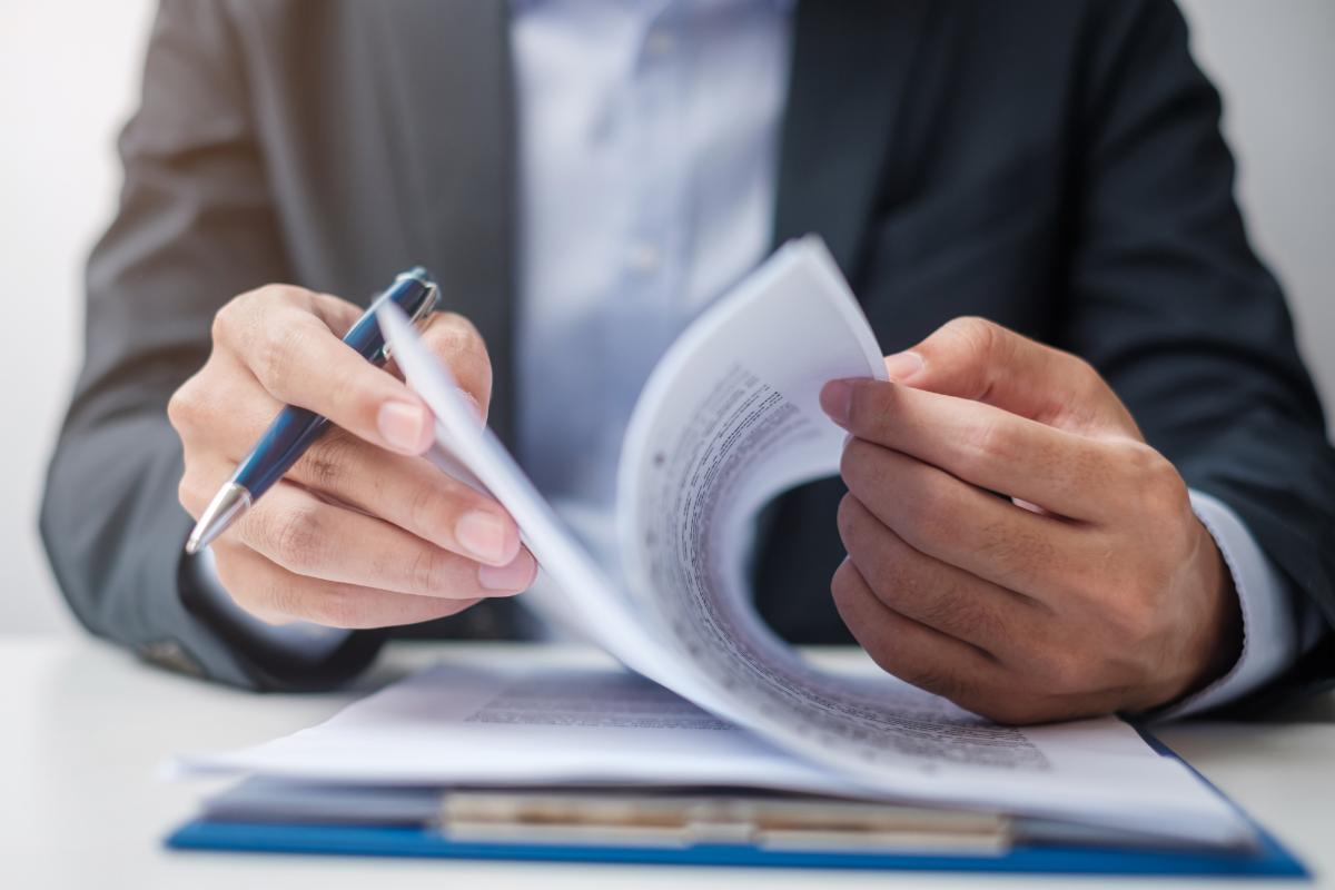 Person reviewing regulations with a pen in hand.