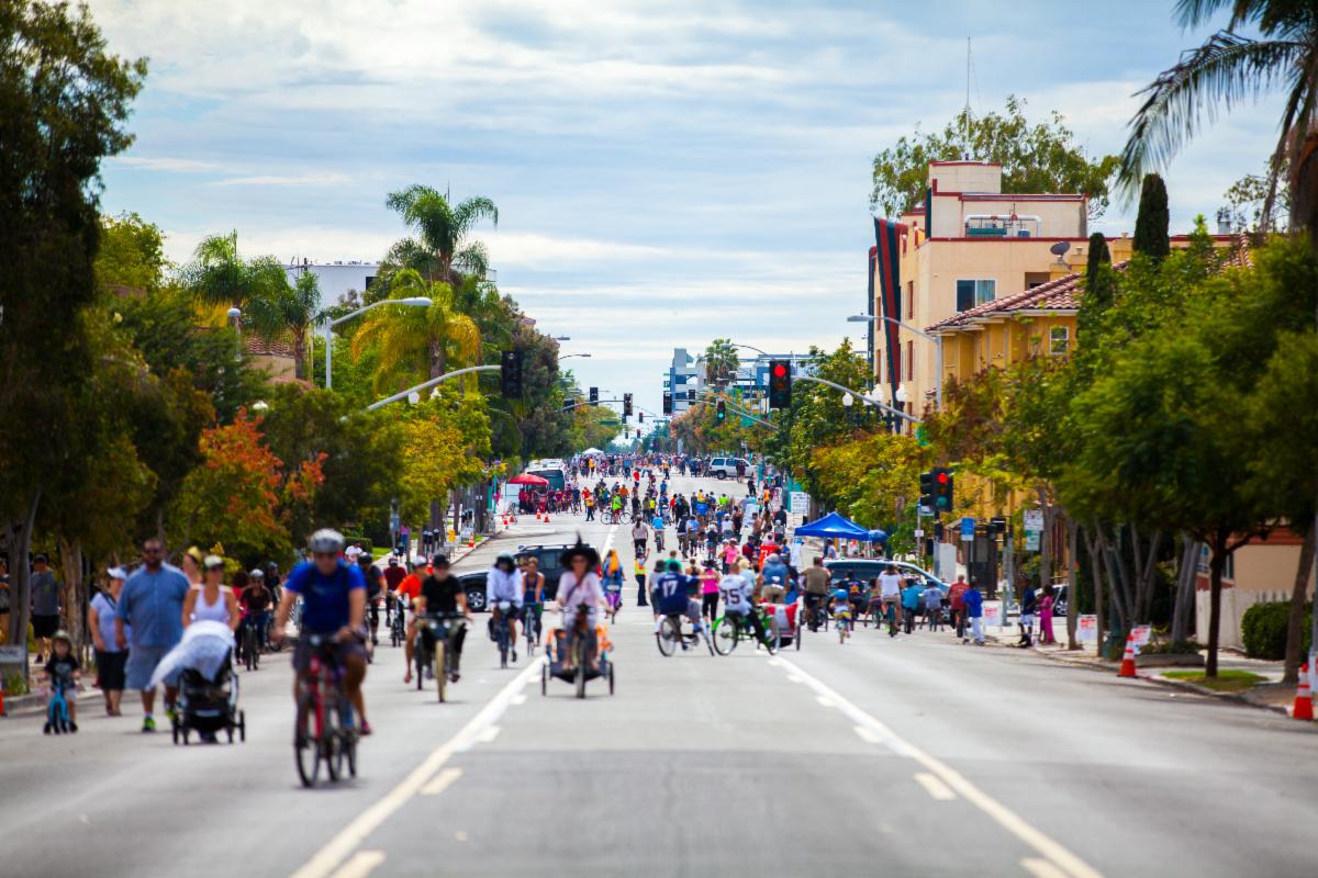 People walking rolling and biking through a street