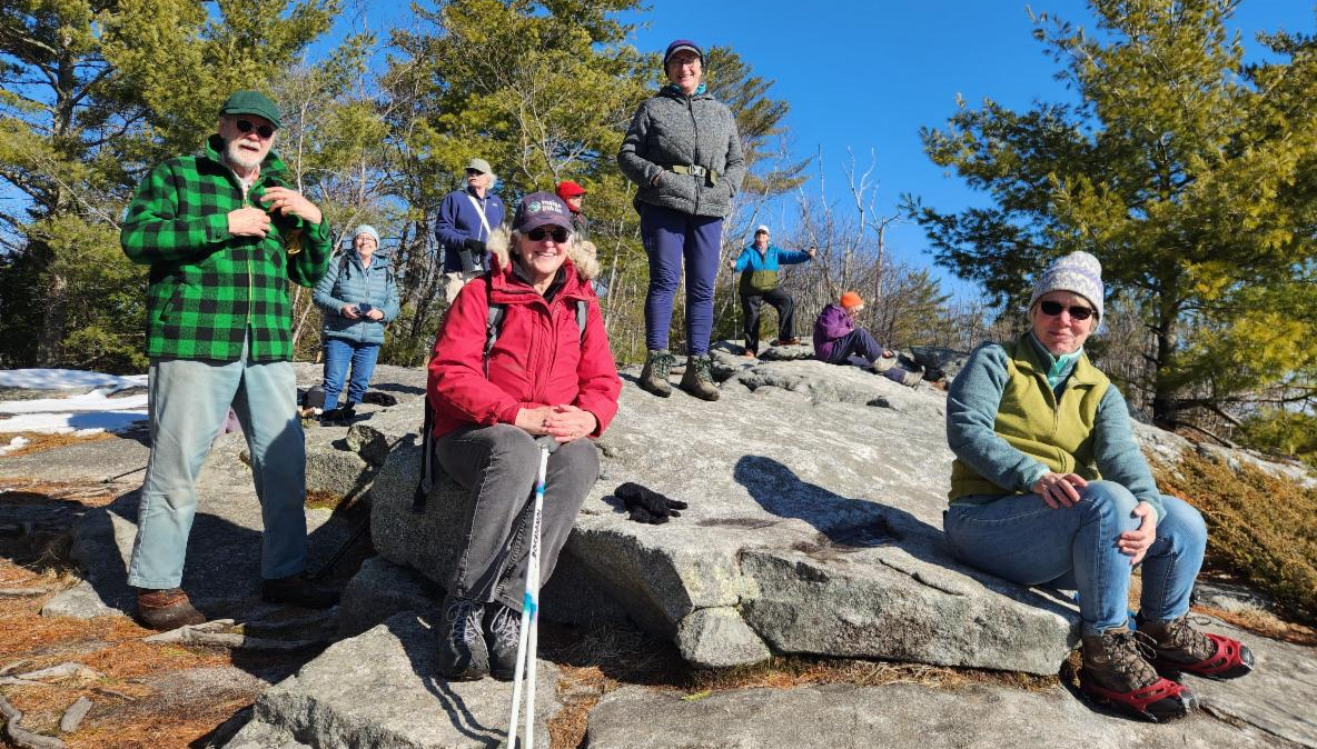 Members of the Gold LEAF Institute dressed in jackets, hiking boots and hats, pose on a rocky slope with hiking poles.