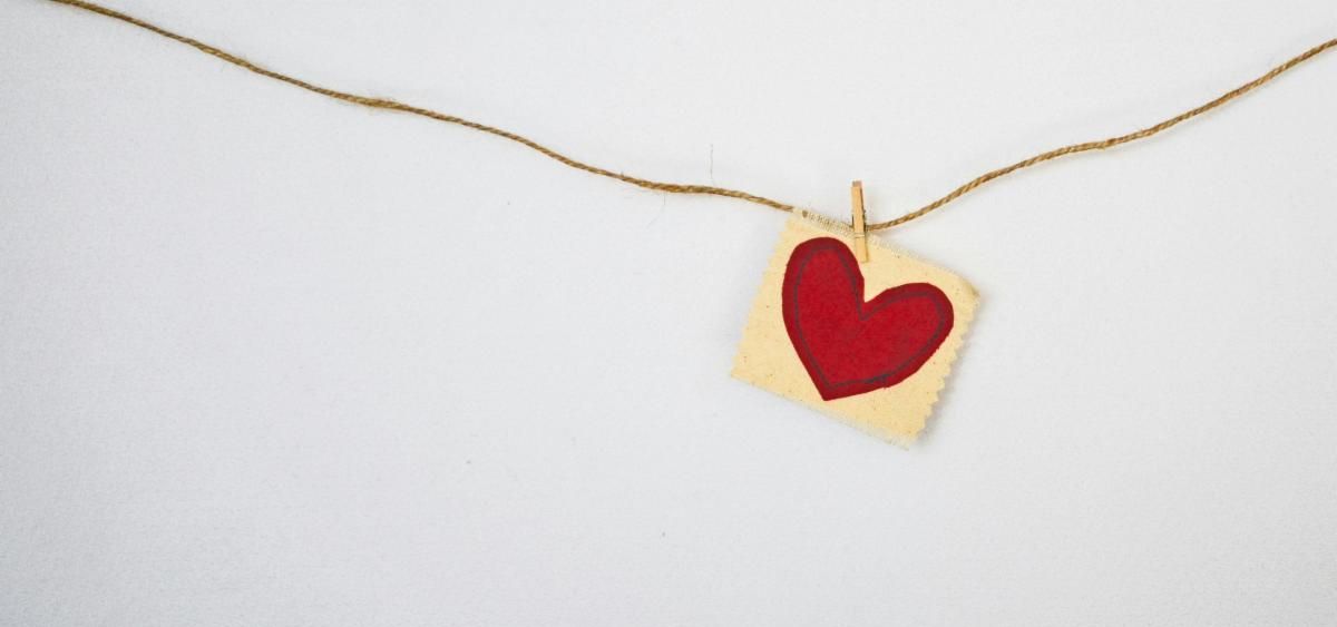 A red paper heart hanging from a twine with a clothes pin