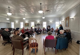 Students sit in a large circle with sheet music